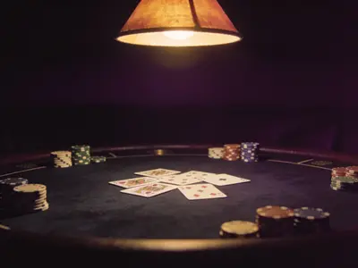 Cards and chips on a dark casino table under a single lamp